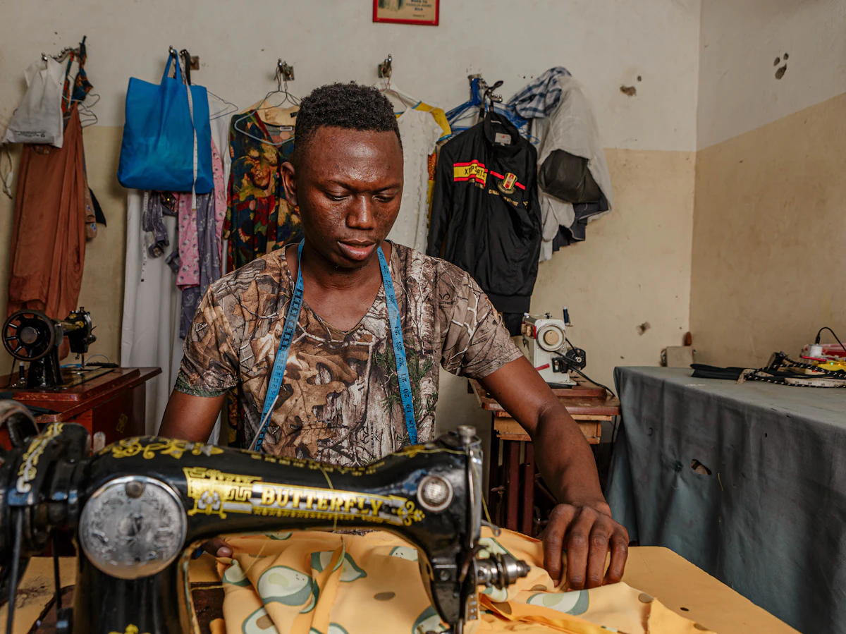 A tailor sewing at a machine in his workshop